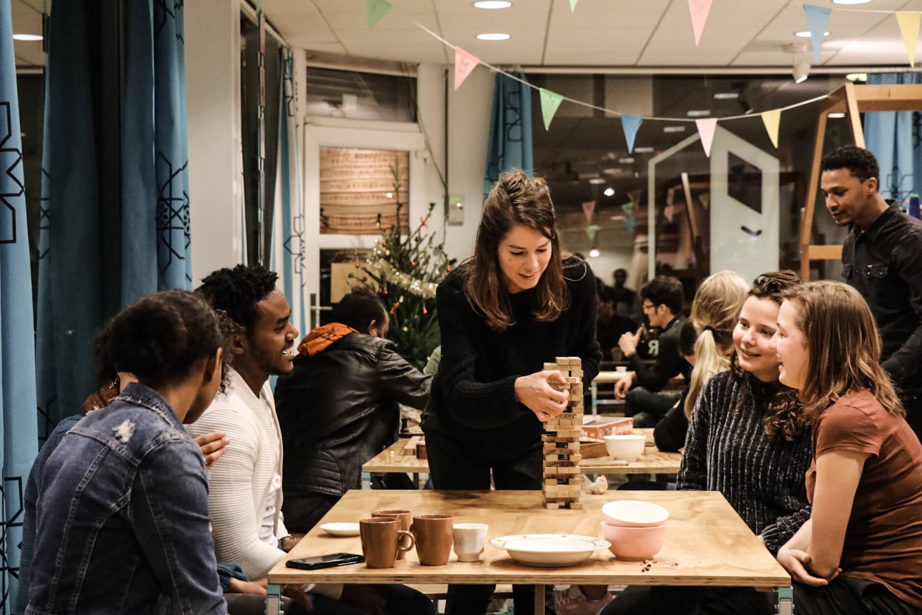 A group playing a wooden block tower game around a table over coffee.