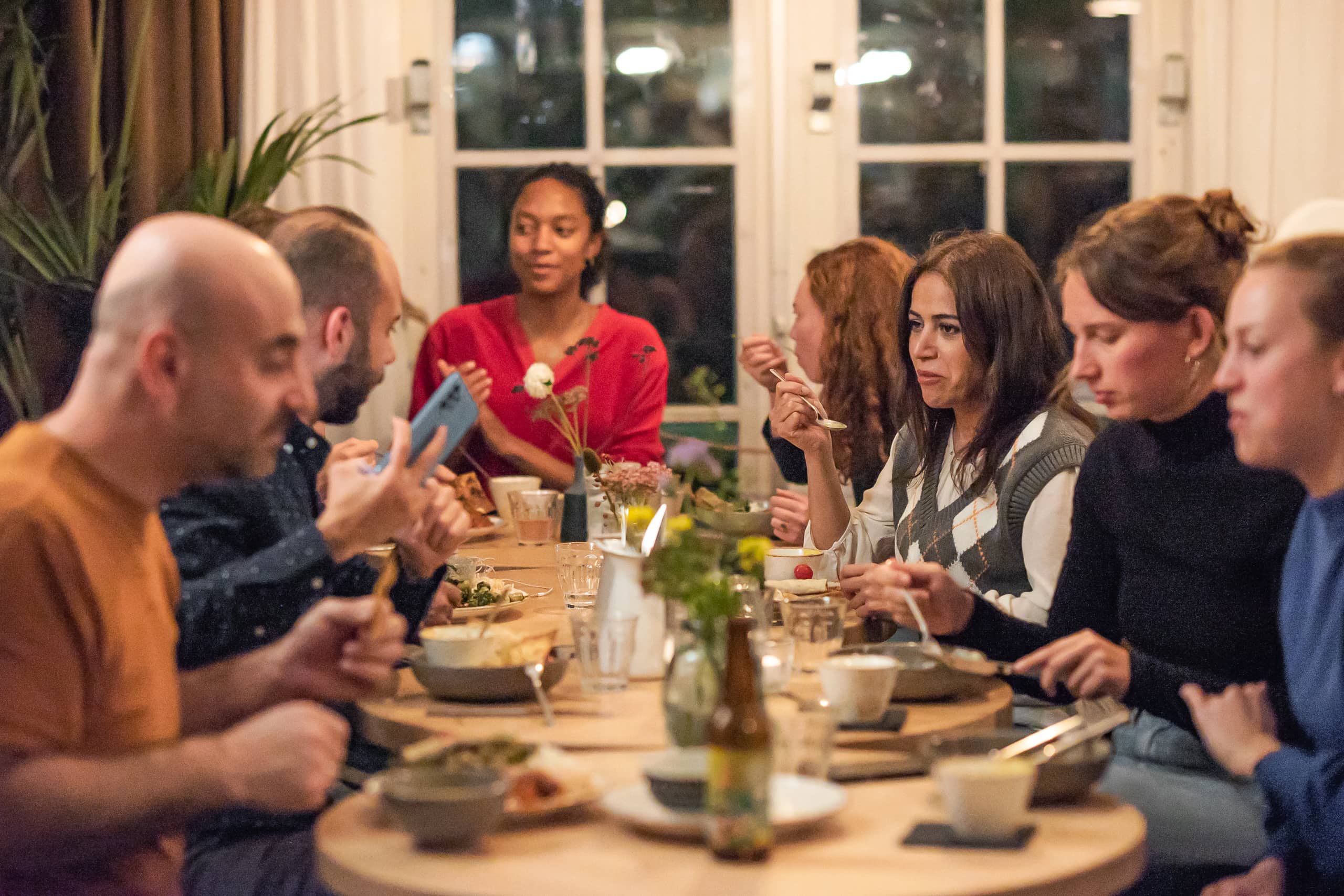 Guests sharing a meal around a round table during a Community Dinner with Buurtbuik.