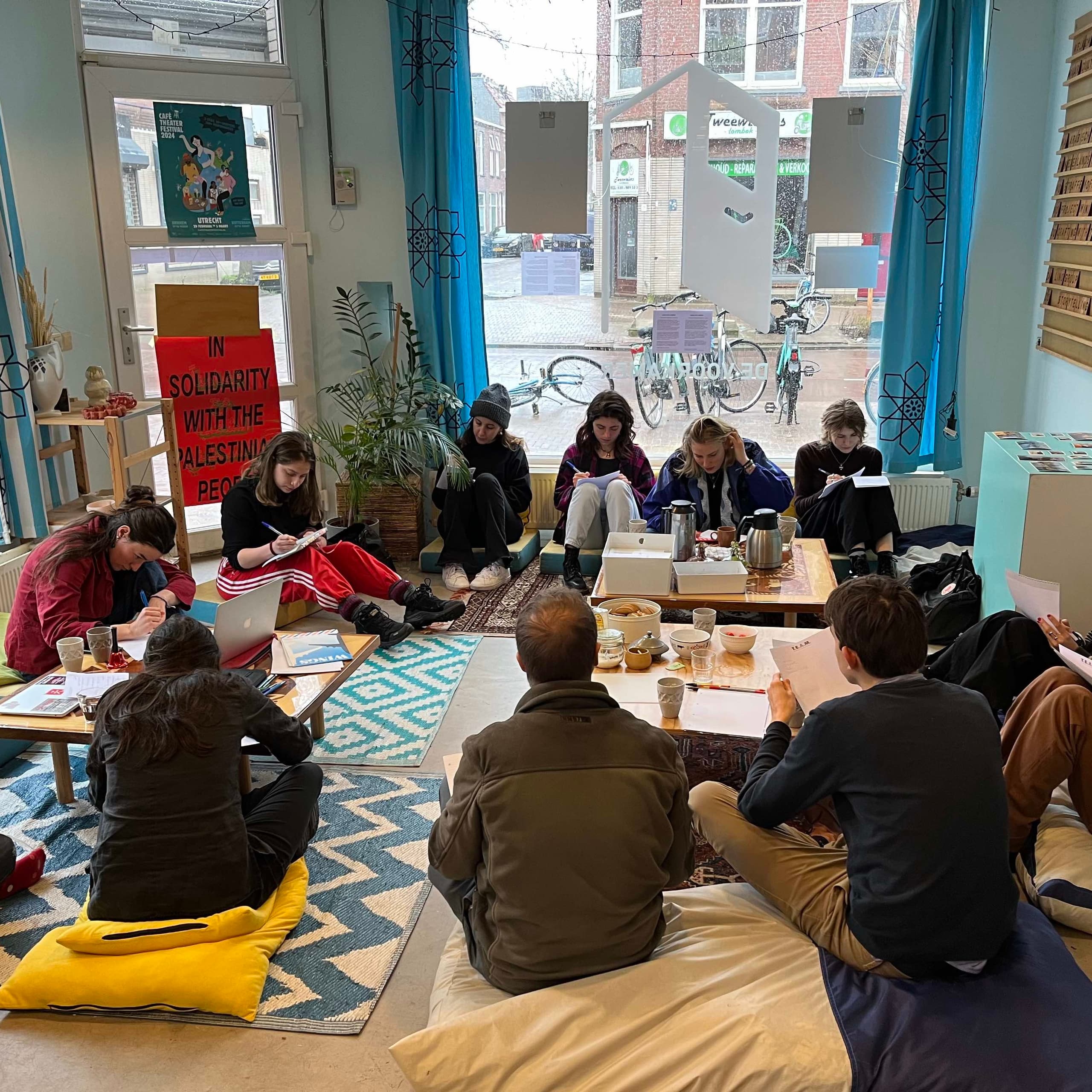 Participants writing on cushions around low tables during a Writing Space session.